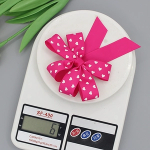 Close-up of rose red ribbed ribbon bow hair clip with white heart patterns