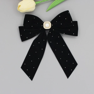 Detail of black velvet bow hair clip with central pearl and rhinestone embellishments