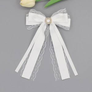 Detailed view of white lace ribbon hair clip with pearl and rhinestone centerpiece