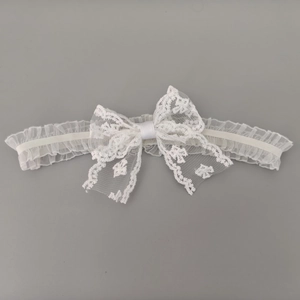 Détail d'un bandeau en dentelle florale blanche avec grand nœud et bordure à volants