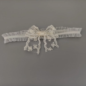 Détail d'un bandeau en dentelle ivoire avec motifs floraux et un nœud élégant en satin