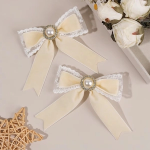 Close-up of cream velvet hair bow with lace trim, pearl center and crystal embellishments