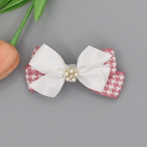 Detail of pink houndstooth and satin bow hair clip with pearl and rhinestone flower