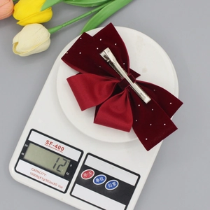 Velvet burgundy double bow hair clip with rhinestones shown on a digital scale weighing 12g