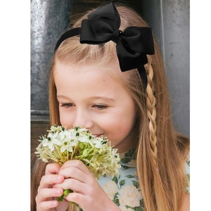 Girl wearing a black ribbed bow headband with a classic sweet and elegant solid color design