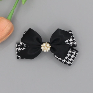 Detail of elegant houndstooth and black satin bow hair clip with pearl and rhinestone center