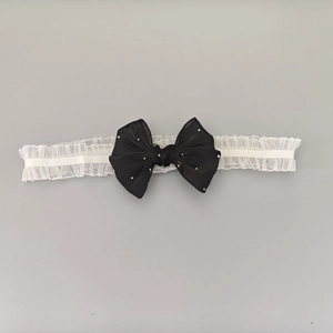 Détail du bandeau en dentelle blanche avec nœud noir pailleté pour bébé fille