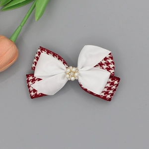Close-up of a handmade houndstooth bow hair clip with white satin and pearl center