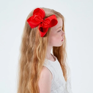 Macro shot of a large red grosgrain ribbon bow hair clip worn by a child model