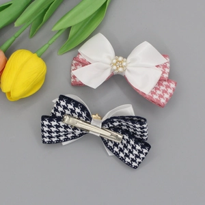 Pink and black houndstooth hair clips with pearls and rhinestones on grey background