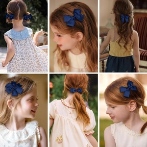Détail des barrettes à nœuds nervurés bleu foncé portées par une enfant en lumière naturelle