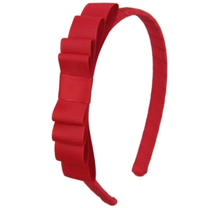 Close-up detail of a bright red multi-layer grosgrain ribbon bow on a slim girl headband
