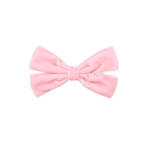 Détail d'une pince à cheveux avec nœud en velours rose et texture de tissu doux