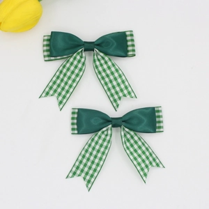 Détail de barrettes à nœuds en satin vert avec rubans à carreaux vert et blanc