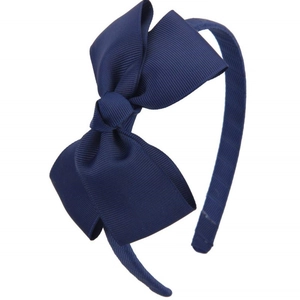 Detailed view of large navy blue grosgrain ribbon bow on a slim headband for girls