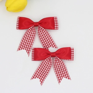Détail de pinces à cheveux avec nœuds rouges à carreaux et satin pour enfants