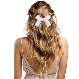 Detail of white satin bow hair clip on blonde hair showing elegant silky texture