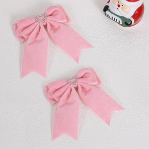 Détail des pinces à cheveux à nœud en velours rose avec strass étincelants en forme de cœur