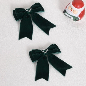 Vue détaillée des barrettes nœuds en velours vert foncé avec centre en strass en cœur