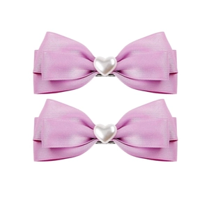 Detail of pink satin ribbon bow hair clips featuring a central white heart pearl embellishment