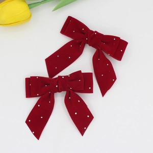 Detail of red velvet bow hair clips with sparkling rhinestones and long elegant ribbons