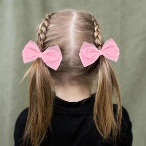 Close-up of pink velvet bow hair clips with organza trim on a girl's pigtails
