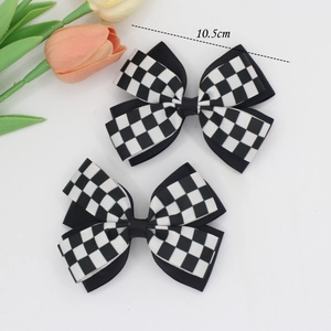 Detail view of 10.5cm black and white checkerboard bow hair clips with satin ribbons