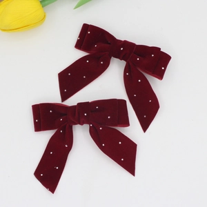 Detailed macro view of burgundy velvet bow hair clips with sparkling rhinestone dots