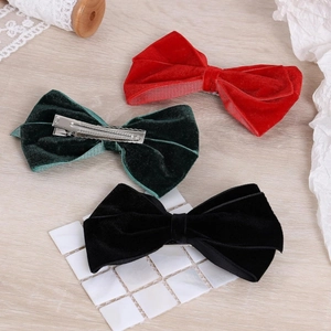 Set of three velvet bow hair clips in red, dark green and black on a rustic background