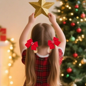 Detail of red ribbon hair bows with heart rhinestones worn by a girl near a Christmas tree