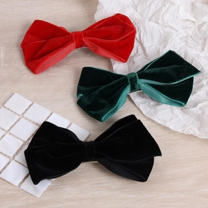 Close-up of red, dark green and black velvet bow hair clips on textured background