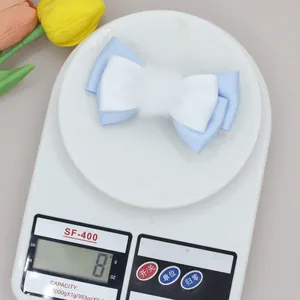 Detail shot showing 8g weight of blue and white bow hair clip with faux fur ball