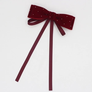Detailed close-up of wine red velvet hair bow with rhinestones and long ribbons