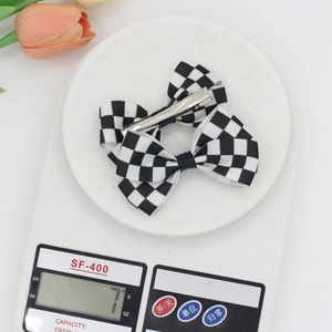 Classic black and white checkered bow hair clip with a silver metal duckbill clip for women