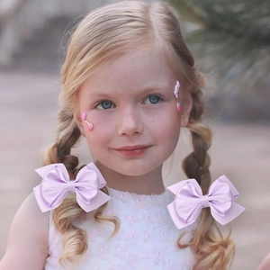 Girl's light purple grosgrain ribbon bow hair clip worn by a child in natural light