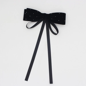 Detail of black velvet bow hair clip with sparkling rhinestones and long elegant ribbons