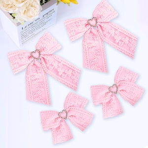 Detail view of four pink lace bow hair clips with heart-shaped rhinestones for girls