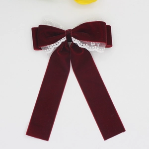 Detail of burgundy velvet bow hair clip with white lace trim and elegant long ribbons