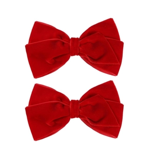 Detailed view of two red velvet bow hair clips with soft fiber texture and double layers