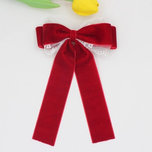 Detail of elegant dark red velvet bow hair clip with white lace trim and long ribbons