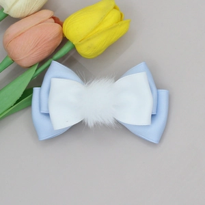 Detail of blue and white bow hair clip featuring a soft faux fur pompom for girls