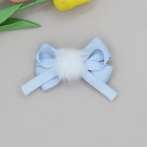 Detail of light blue ribbon bow hair clip with a white faux fur ball for girls