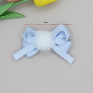 Close-up of 9cm light blue ribbon bow hair clip featuring a soft white plush pom-pom detail