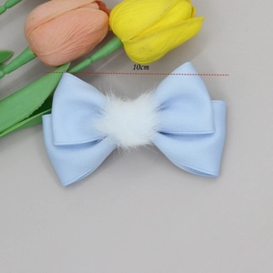 Detail showing 10cm light blue bow hair clip with white plush ball and satin texture