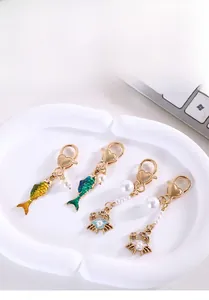 Detailed shot of fish and crab metal pendants with pearls and heart lobster clasps