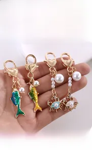 Detail of colorful enamel fish and crab charms with pearls and heart-shaped clasps