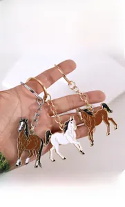 Detailed close-up of colorful enamel running horse keychains in brown and white finish