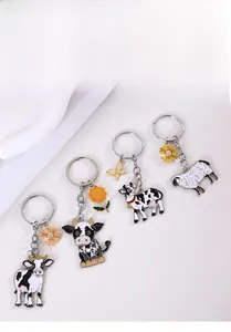 Détail de quatre porte-clés en métal vache et mouton avec pendentifs fleur et papillon