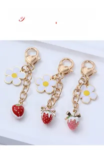 Detailed close-up of white enamel flower and strawberry metal pendants with heart clasps