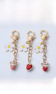 Detailed view of white daisy flower and pink strawberry enamel charms with heart clasp